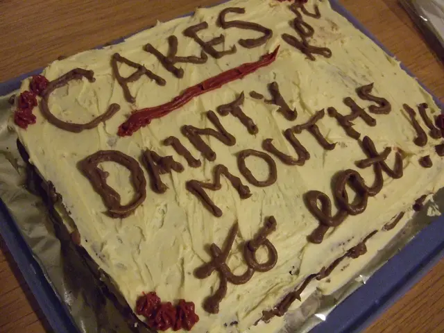 In the center of the image, we can see a cake on the tray and there is some text on it. At the...